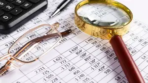 A tax document with glasses and a magnifying glass resting on top of it.