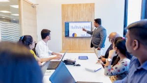 A financial advisor presenting business performance charts and graphs to a small business team in a conference room, representing outsourced CFO services and strategic financial planning.